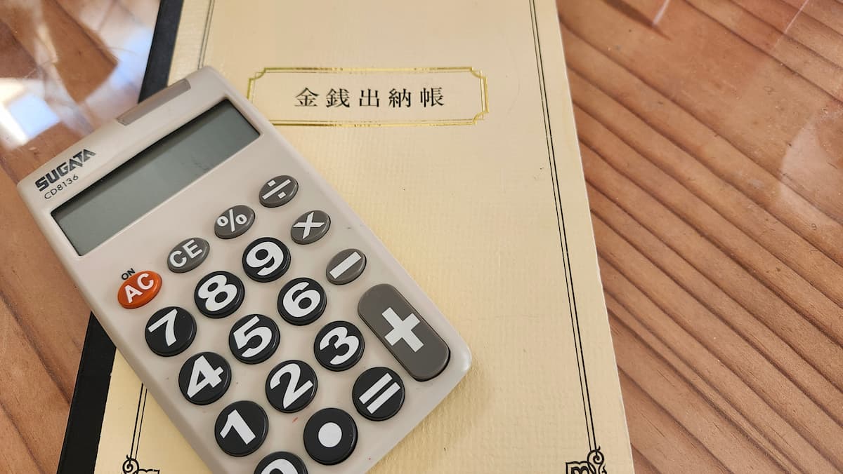 電卓と金銭出納帳が机に乗っている様子