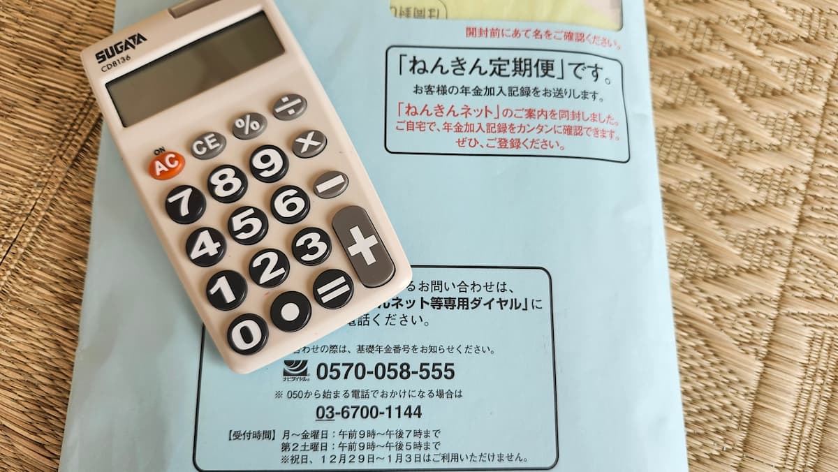 畳の上に 年金定期便の封筒と電卓がある様子