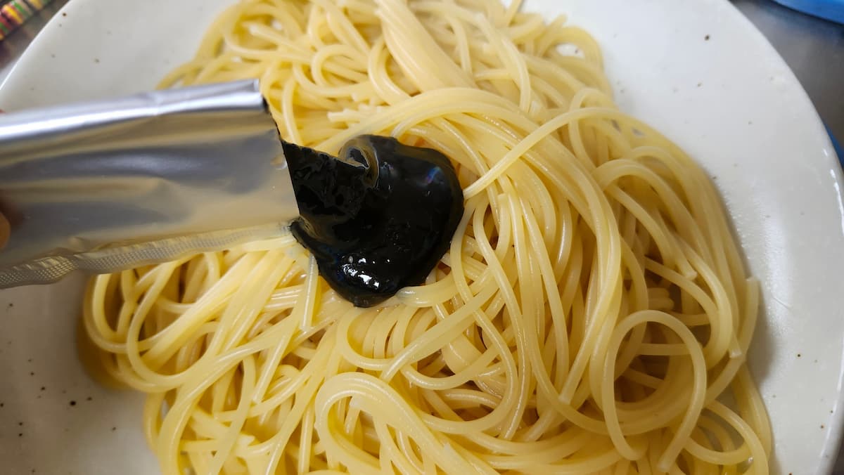 無印良品のイカすみソースをパスタにかける様子
