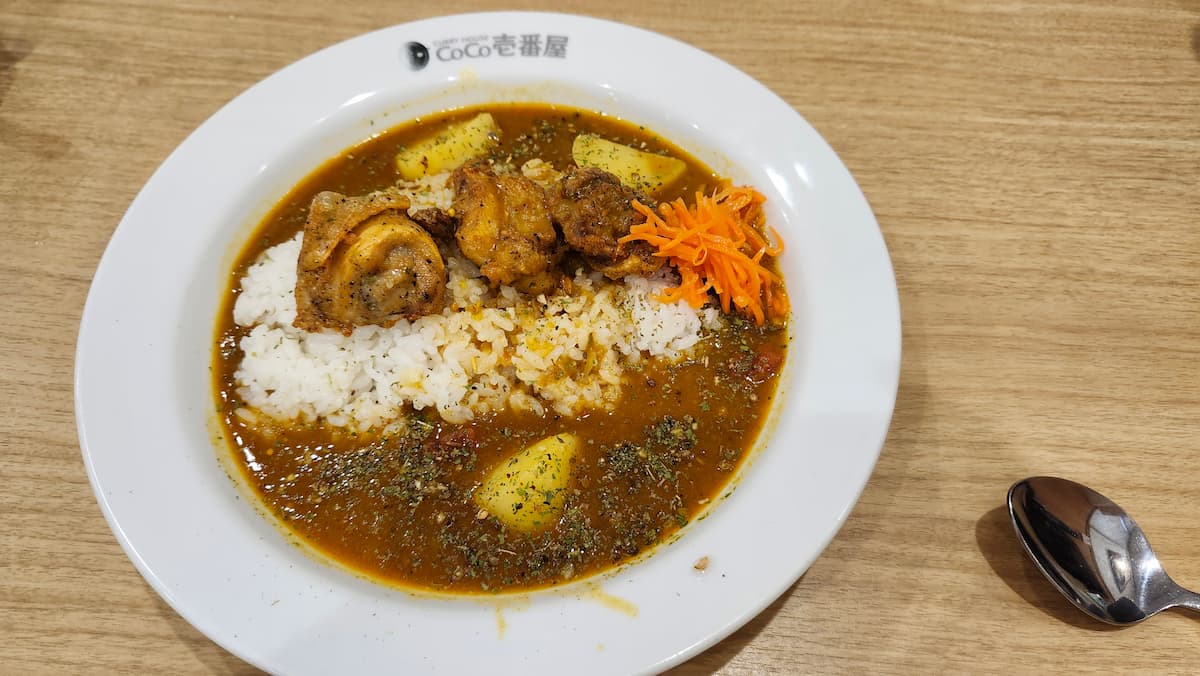 テーブルの上に置いたココイチのケララチキンスパイスカレーとスプーン